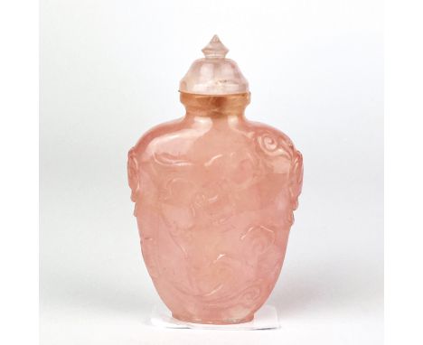 A Chinese carved rose quartz snuff bottle decorated with dragons and lion ring side handles, H. 8.5cm.