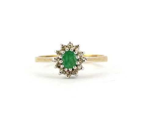 A hallmarked 9ct yellow gold ring set with an oval cut emeralds and diamonds, (M).