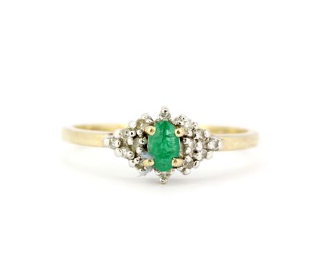 A hallmarked 9ct yellow gold ring set with an oval cut emerald and diamonds, (N.5).