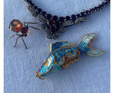 A 20th cent yellow metal enamel fish pendant, a yellow metal spider brooch and a white metal and garnet necklace&nbsp;
