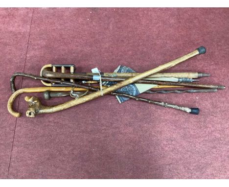 A collection of walking sticks to include one barley twist design, one with a white metal collar, shooting stick, umbrella et