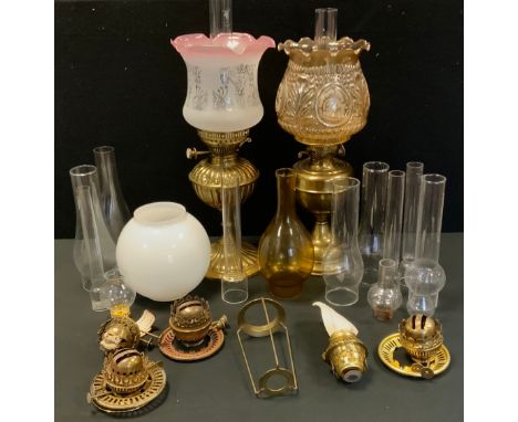 A Victorian brass oil lamp, embossed body and reservoir, frosted glass shade, another plain, assorted spare burners, chimneys