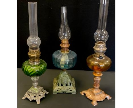 A Victorian oil lamp, ornate cast iron base, aquamarine blue glass reservoir;  others gilt metal, amber and green reservoirs,