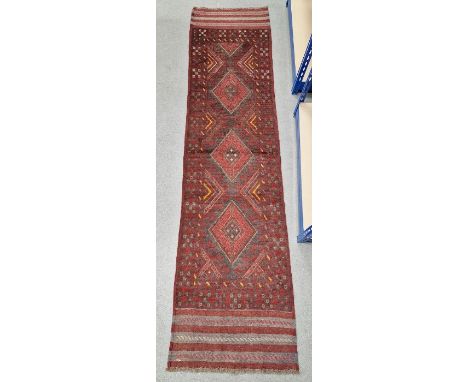 Red ground Meshwani runner with three central lozenge medallions, multiple geometric borders, 250cm x 62cm&nbsp;Condition Rep