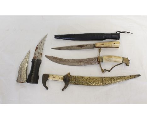 Group of four daggers to include Arabian Jambya dagger in white metal scabbard and Cretan dagger in leather scabbard and bone