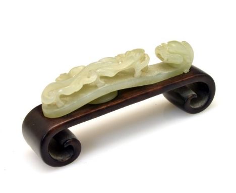 19th Century Chinese carved jade belt hook of traditional figural form, 10cm long on a hardwood stand  Condition: No obvious 