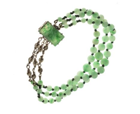 Three row jade bracelet, to a carved jade panel clasp, the beads of approximately 3.5mm to 7.5mm, approx 25.9g gross  Conditi