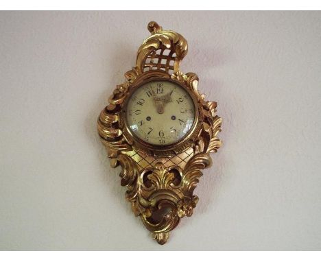 A Swedish 20th century Rococo-styled carved and gilded wood-cased cartel wall clock, cream painted dial with Arabic numerals 