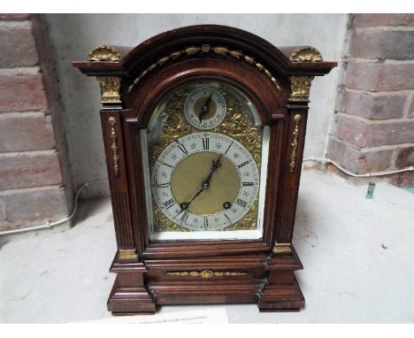 An impressive table clock, oak cased with cast ormulu mounts, opening door with heavy bevelled glass, arched brass dial with 