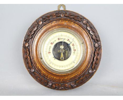 An oak cased barometer with oak leaf carved detail, approx 23 cm (diameter)