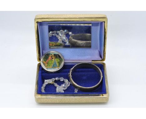 A vintage jewellery box containing a hallmarked silver bangle with safety chain, a graduated crystal necklace and a unusual w