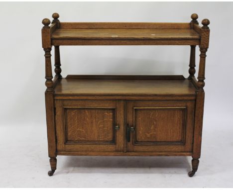 AN OAK BUFFET on turned supports with two panelled doors, turned feet and ceramic castors 104cm wide 