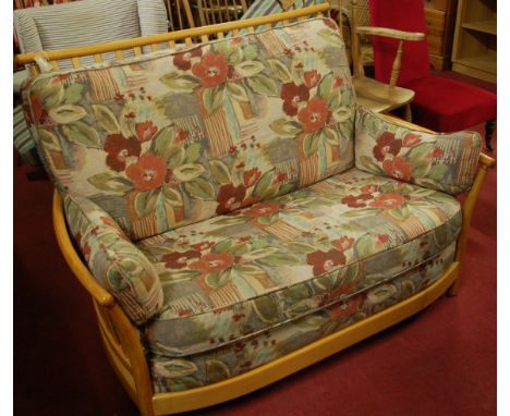 A contemporary Ercol blond elm slatback two seater sofa, having bright coloured floral cushion upholstery