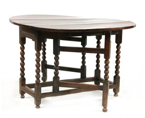 A Charles II oak gateleg dining table, the oval drop-leaf top over a single frieze drawer, bobbin turned legs and square stre