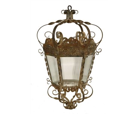 A large wrought iron hexagonal lantern, 20th century, with scrolling supports and ribbed glass shade, 100cm high