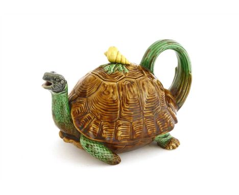 A Minton majolica tortoise teapot and cover, with a green body and brown shell with a seashell finial to the cover, enclosing