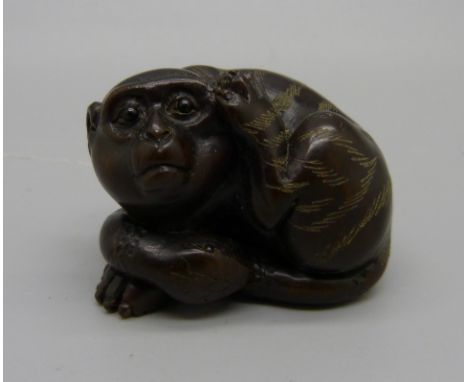 A carved Japanese netsuke of a monkey, signed 