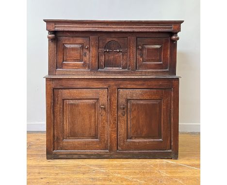 An 18th century oak court cupboard of pegged contruction, the projecting top over channel moulded frieze, twin fielded panell