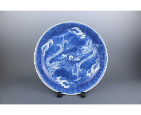 A large Chinese blue and white “dragon” dish, Qing Dynasty Kangxi period (1662-1722), heavily potted and decorated in reserve