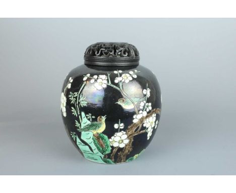 A Chinese famille noire ovoid jar and wooden cover, Qing Dynasty 19th century, finely decorated with two magpies chirping at 