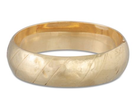 A VINTAGE GOLD HINGED HOLLOW BANGLE, with engraved decoration, 24 g. *** testing as 55%