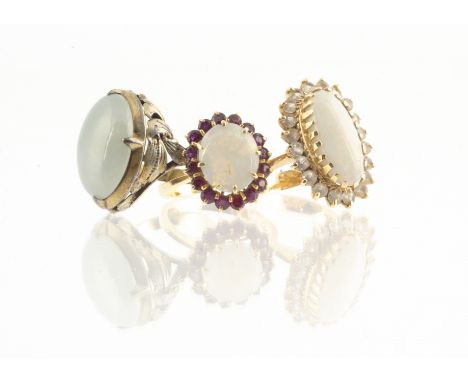 Two 18ct gold white opal dress rings, both claw set, one with white sapphire bezel, the other set with garnets, marked 750 an