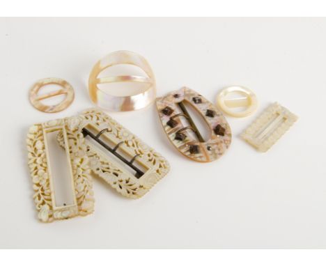 A collection of mother of pearl buckles, including two floral carved examples, another of buckle shape with steel stud design