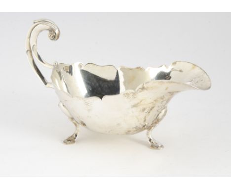 A George V silver sauce boat from Sir JBL Ltd, on three supports with shaped rim and C scroll handle, 7.85 ozt, London 1932