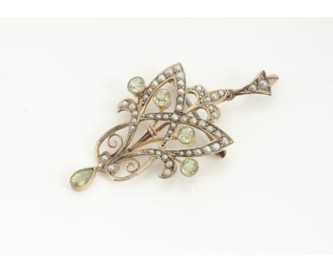 An Edwardian peridot and seed pearl 9ct gold pendant or brooch, in the Art Nouveau style, the pierced frame centred with a go