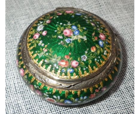 A CONTINENTAL ENAMEL AND SILVER PILL BOX of circular form with floral and scrolling decoration, against a green ground