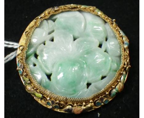A CARVED 'JADE' DISC in a yellow metal and enamel decorated mount