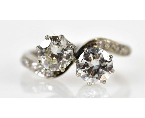 A platinum and diamond crossover ring, each old cut round claw set diamond approx 0.85cts, with tiny accent diamonds to the s
