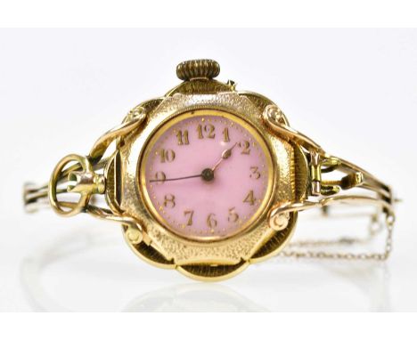 An unusual hinged bangle set with a 14ct yellow gold crown wind watch with Arabic numerals to the pink dial and with enamel d