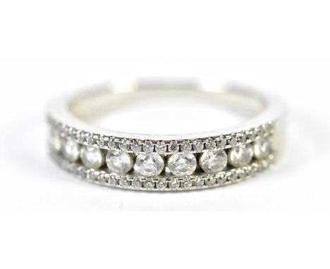 A white metal diamond half eternity ring with central channel set row of nine round brilliant cut stones flanked by twin rows