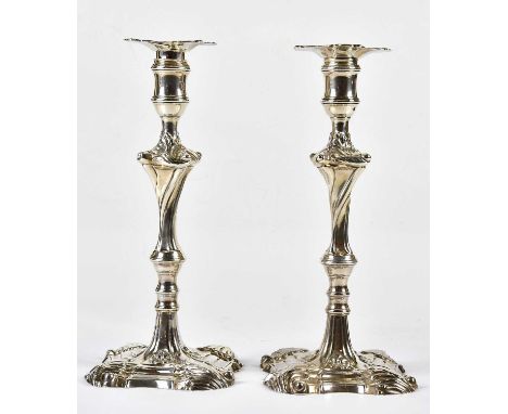 EBENEZER COKER; a pair of George III hallmarked silver candlesticks with cast open shell and floral decoration, London 1764, 