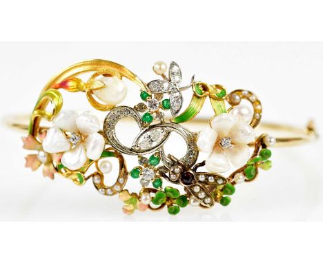 An Edwardian yellow metal diamond, emerald, pearl and enamelled oval hinged bangle with pierced floral detail set with an ins