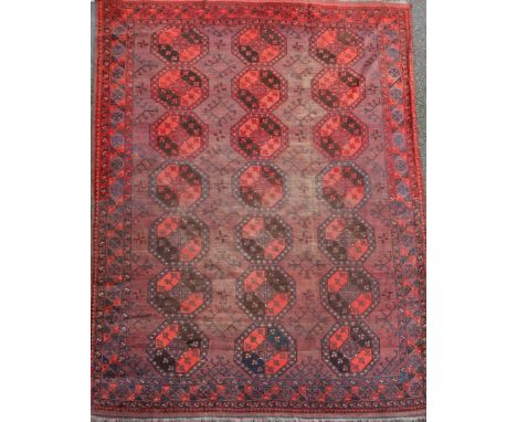 An Afghan aubergine and red ground carpet, with field of octagons and geometric motifs, 350 x 274cm Condition: Generally show