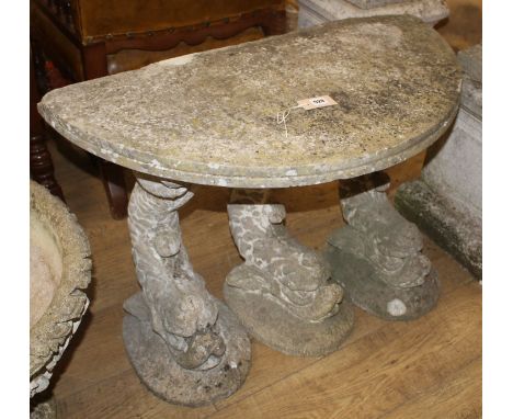 A reconstituted stone demi lune garden seat, on dolphin supports, W.90cm D.45cm H.80cm Condition: Weathering and lichen comme