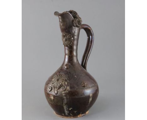 A Turkish Cannakale pottery ewer, 19th century, applied with medallions and scroll decoration and covered in a dark brown gla