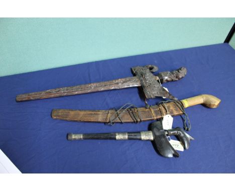 Two Kris knives, one with ornately carved hilt and scabbard, with a parang latok