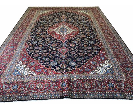 FINE PERSIAN KASHAN CARPET, 415cm x 305cm, pendant medallion on a midnight blue field of palmettes and vines within correspon