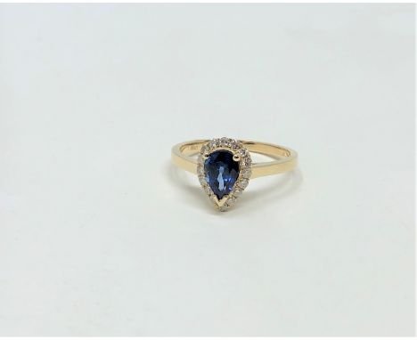 A 14ct yellow gold sapphire and diamond ring featuring centre pear cut blue sapphire (1.06ct), claw set with sixteen round br