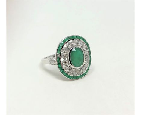 An 18ct white gold emerald and diamond Art Deco style ring, featuring oval cut vivid green emerald (2.06ct), twenty seven Fre