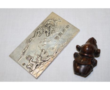 A Japanese carved wood netsuke in the form of a toad 2¼" long and an Eastern silvered rectangular medallion with dragon decor