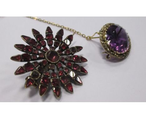 A foil backed ruby flowerhead brooch, the round central stone surround by tapered petals comprising of three smaller stones a