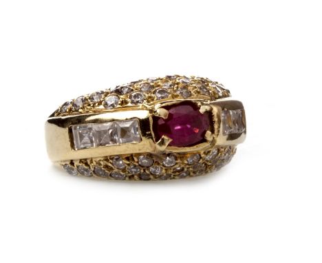 GEM SET RING, in the form of a tapered band, with a central oval faceted red gem 6.5mm long and flanked by two rows of channe