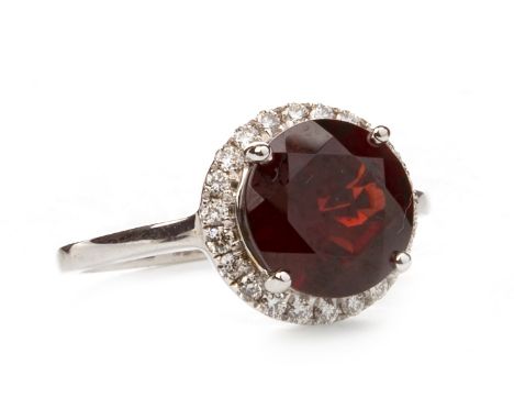 CLOGAU GOLD RODALITE GARNET AND DIAMOND RING, set with a central round faceted garnet 9.8mm diameter within a diamond halo, m