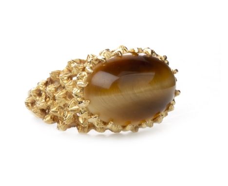 TIGER'S EYE SET RING, set with cabochon section of tiger's eye 15mm long, with moulded decoration to the shoulders, marks ind