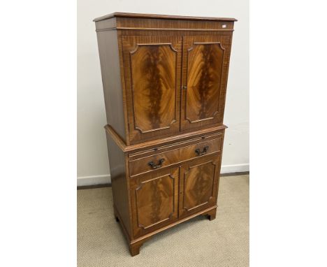 A modern mahogany cocktail cabinet, the plain top above two doors opening to reveal a mirrored interior to glass cupboard bru