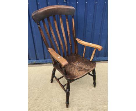 A late Victorian beech and elm slat back Windsor type armchair, on turned legs united by stretchers, the seat stamped with ma